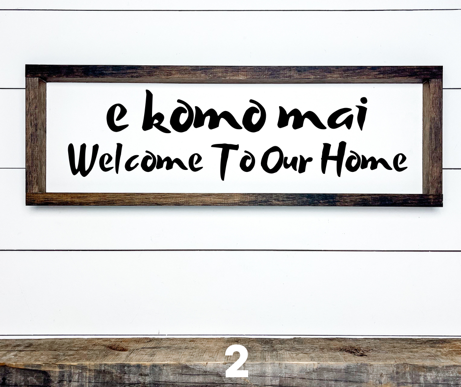 Hawaiian E Komo Mai Welcome wood sign with tropical floral accents, shown hanging on a front door for island-style entryway decor.