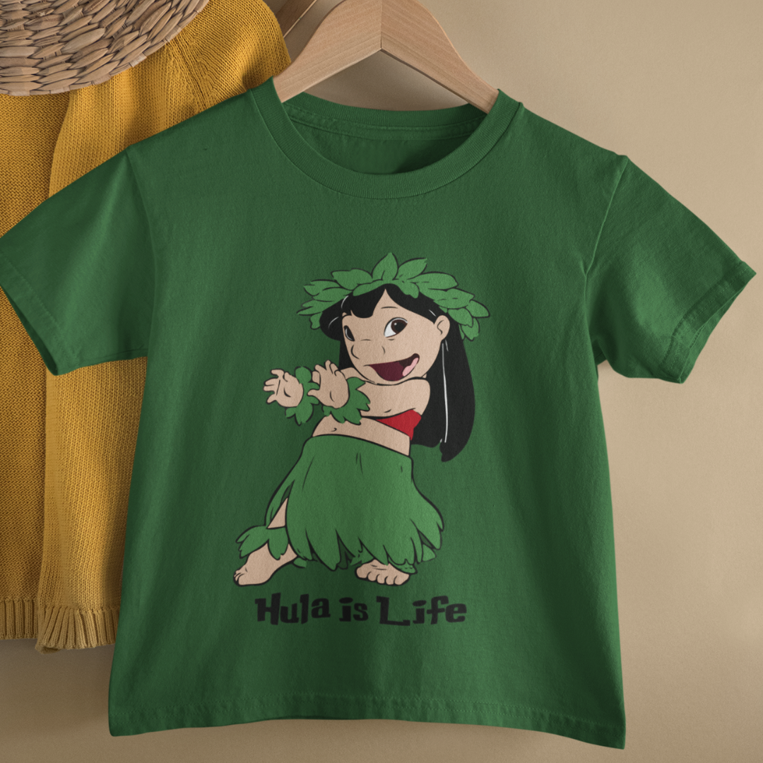A green kids t-shirt on a hanger that says "Hula Girl" with a graphic of a girl dancing the hula, a Hawaiian dance shirt on a hanger