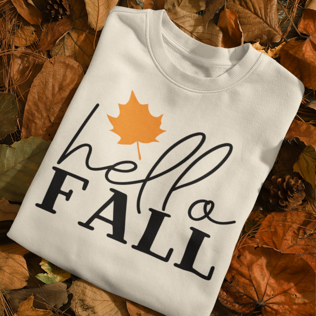 White sweatshirt withHello Fall and a leaf design on autumn leaves in a forest by Simply Aloha On the Go™