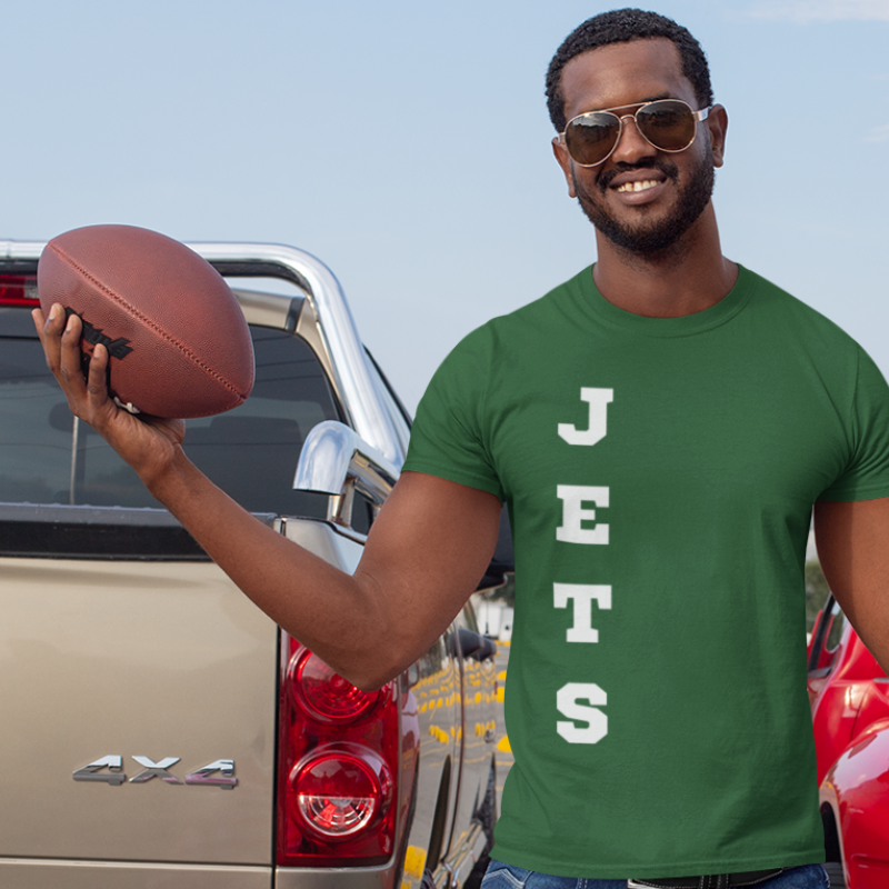 A man at a tailgate party wearing a personalized green men's game day t-shirt featuring vertical white text reading "JETS"