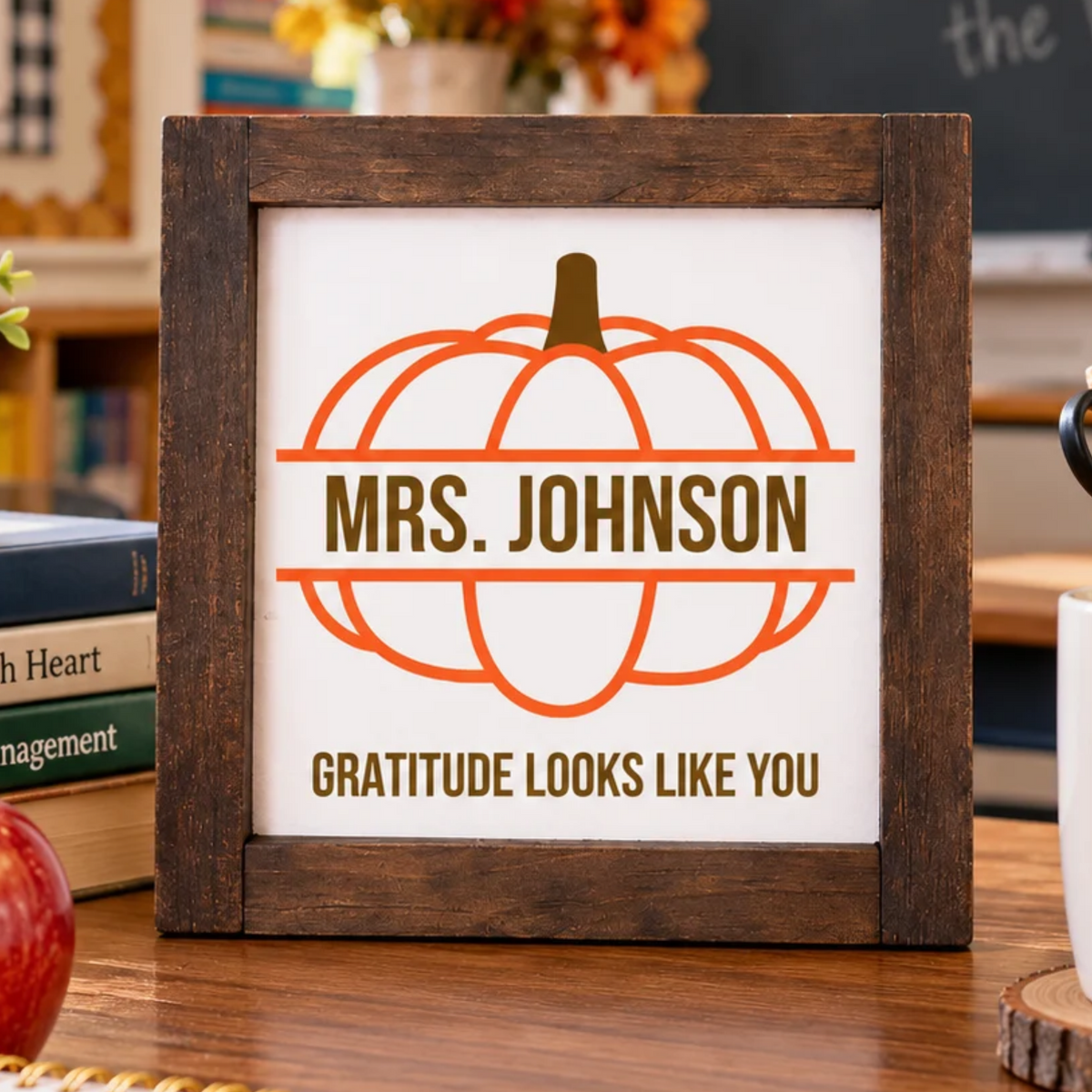 Personalized Teacher Appreciation Pumpkin Sign displayed on a teacher’s desk in a cozy classroom with books, pencils, coffee mug and fall decor