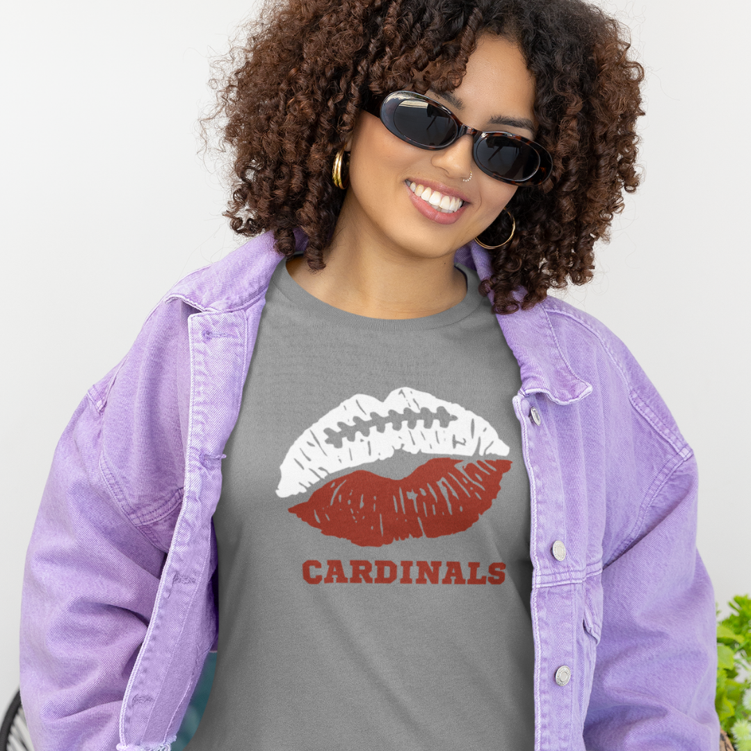 A woman wearing game day t-shirt in grey color with a lip-themed design in red and white on top and the team name Cardinals written below.