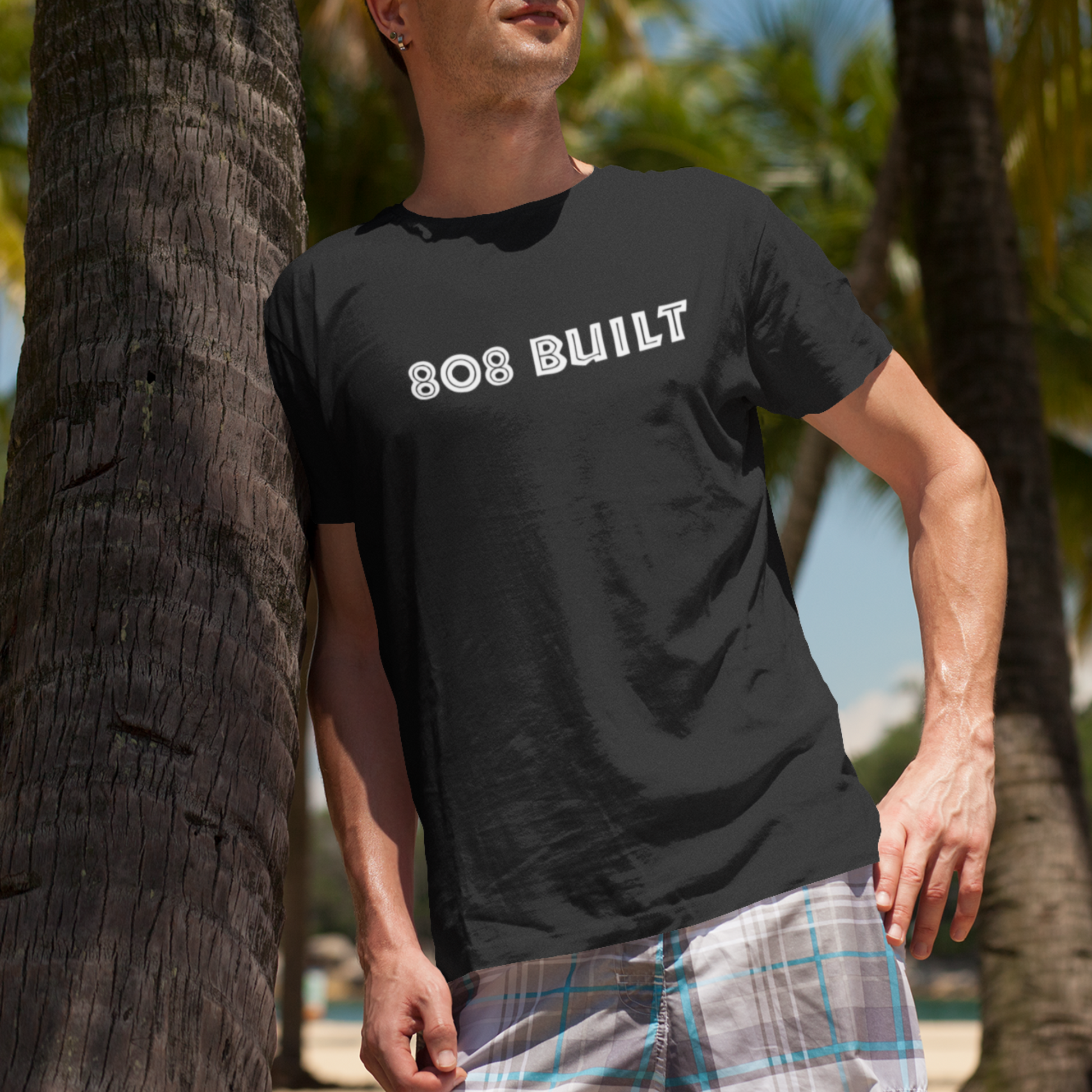 Man wearing the 808 Built Hawaii T-Shirt, which features a double-sided graphic print for local pride, styled for casual wear.
