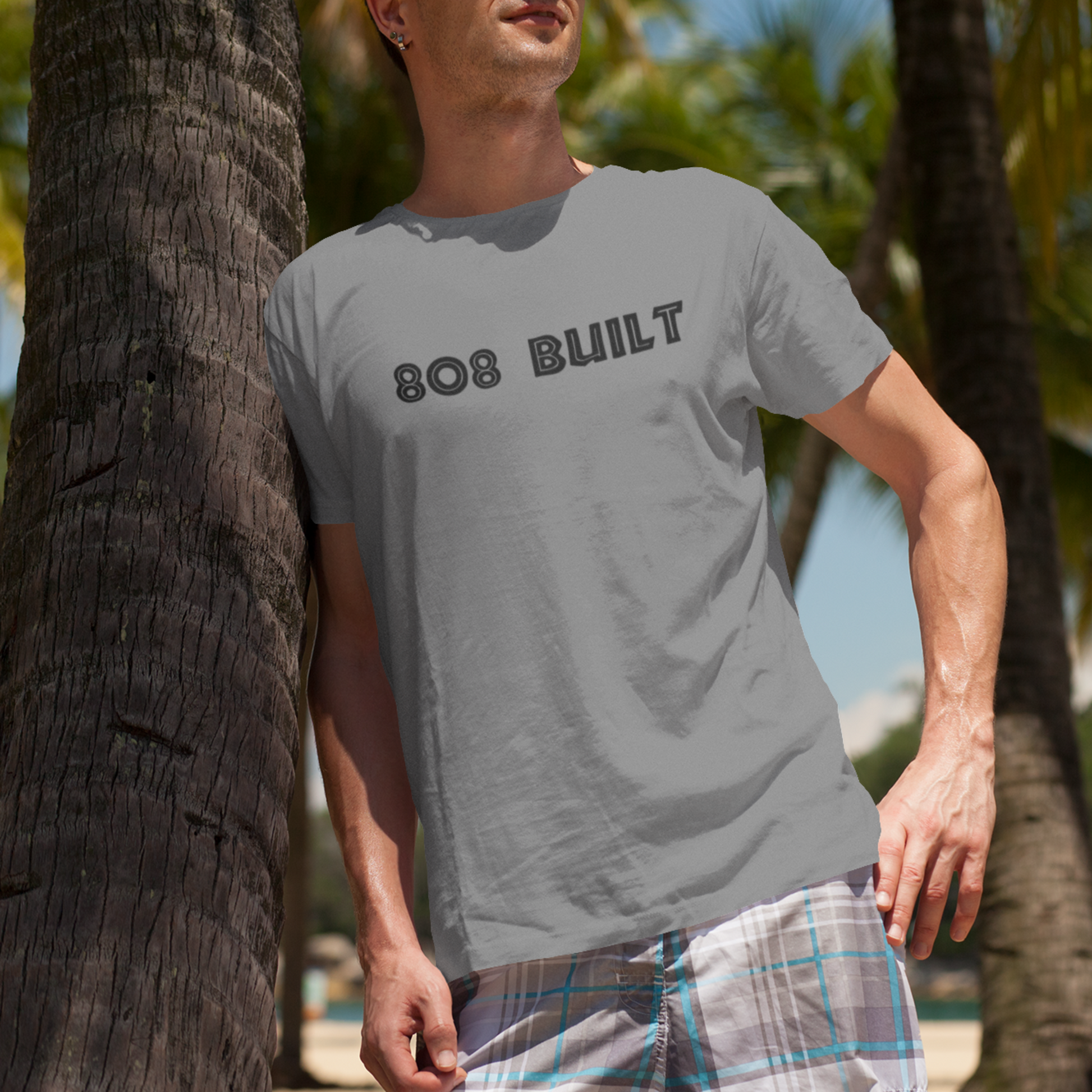 Man wearing the 808 Built Hawaii T-Shirt, which features a double-sided graphic print for local pride, styled for casual wear.
