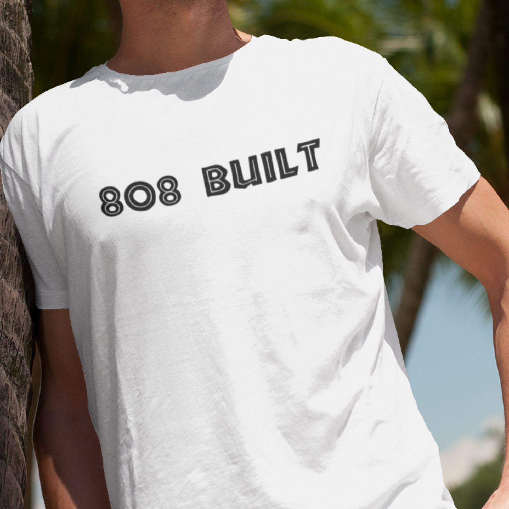 Man wearing the 808 Built Hawaii T-Shirt, which features a double-sided graphic print for local pride, styled for casual wear.

