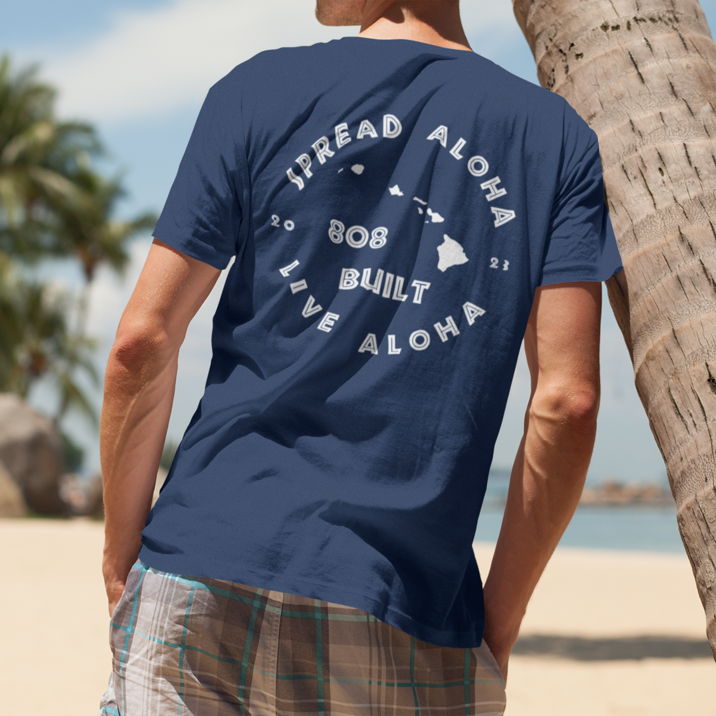 showcasing the back design of a white custom t-shirt with a bold circular graphic that reads Spread Aloha Share Aloha 808 Built Hawaii.