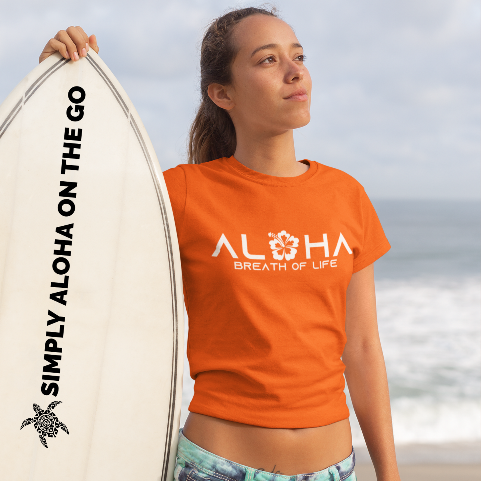 A woman wearing an "Aloha Breath of Life" t-shirt with a hibiscus design, an island-inspired shirt.