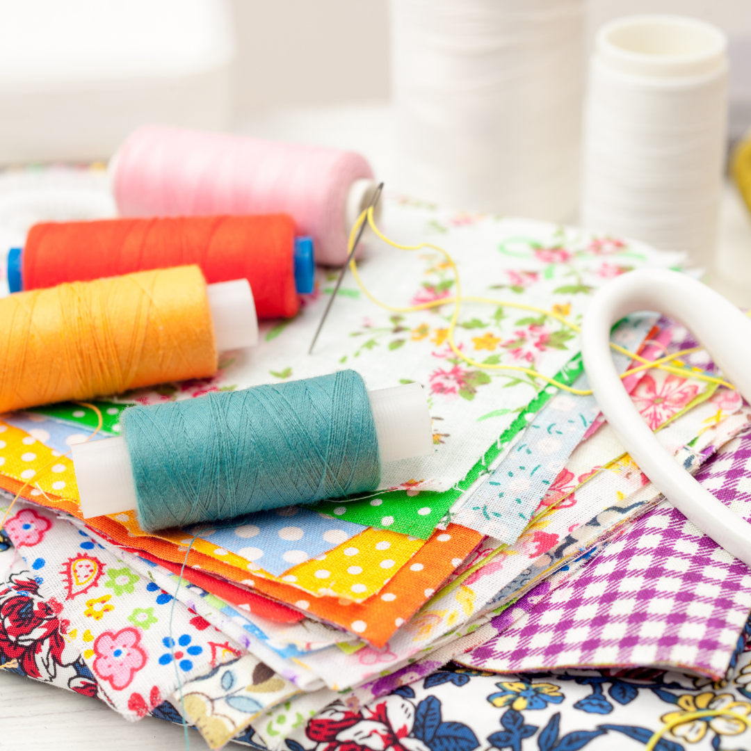 Colorful spools of thread and fabric samples on a white surface