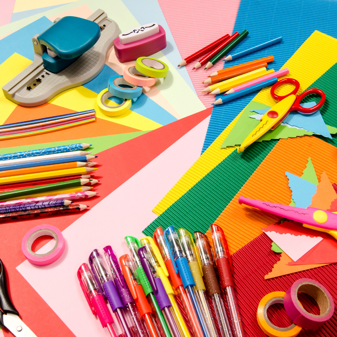 Colorful stationery items including pens, pencils, scissors, and paper on a multicolored background
