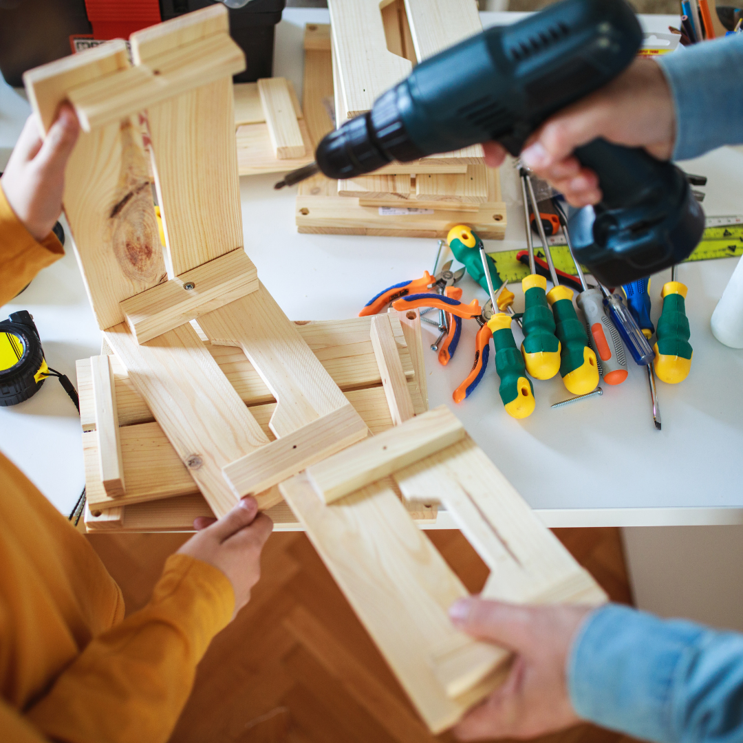 Two people working on a wooden project with tools on a table