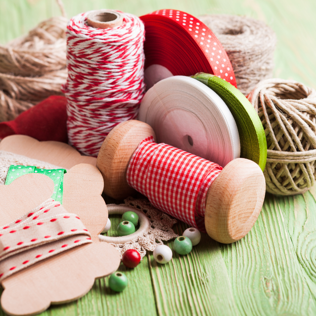 Spools of red and white checkered, red, and green ribbon on a wooden surface with decorative elements.