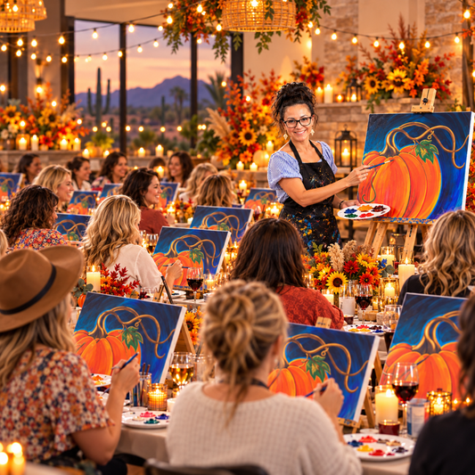 Woman teaching a pumpkin paint party live at an Arizona mobile paint party, surrounded by guests painting fall pumpkin canvases in a cozy candlelit sip and paint setting.