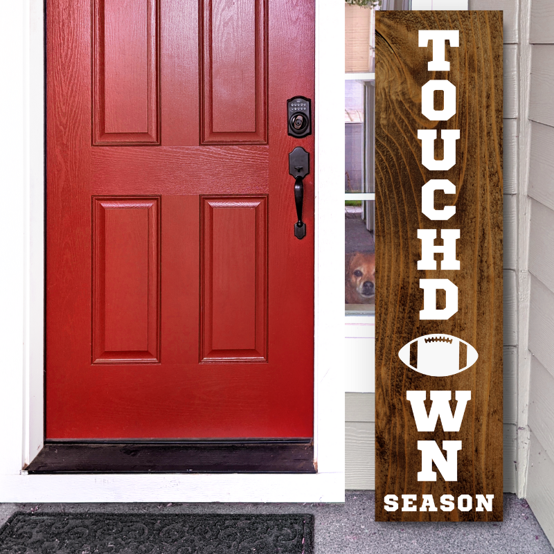 Handcrafted wooden vertical porch leaner sign that reads "Touchdown Season" with a football graphic, displayed next to a front door.