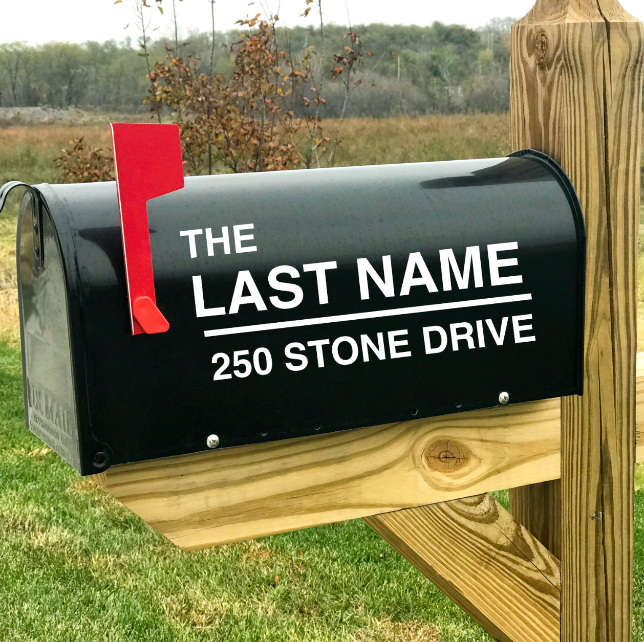 Custom white vinyl decal featuring a personalized home address and last name applied to a black curbside mailbox.