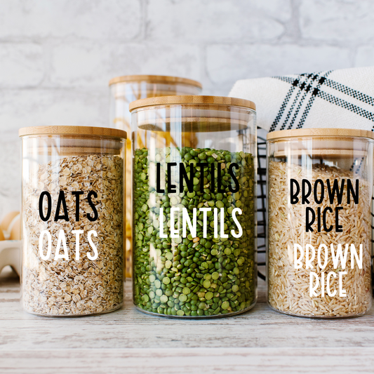 A set of white custom storage labels on clear pantry containers, for home organization.