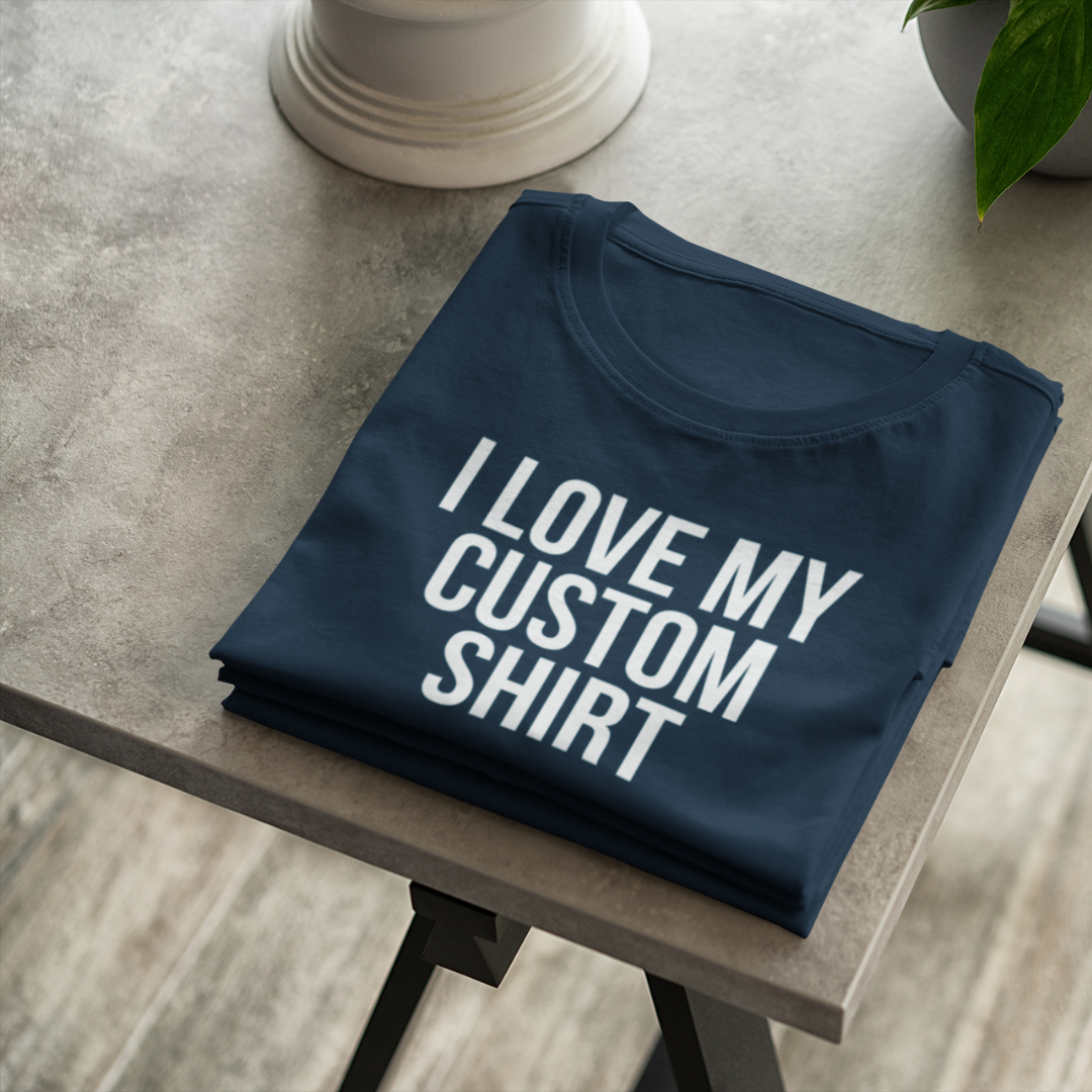 A flat-lay view of a blue custom personalized t-shirt displaying a bold white text graphic that reads I Love My Custom Shirt.
