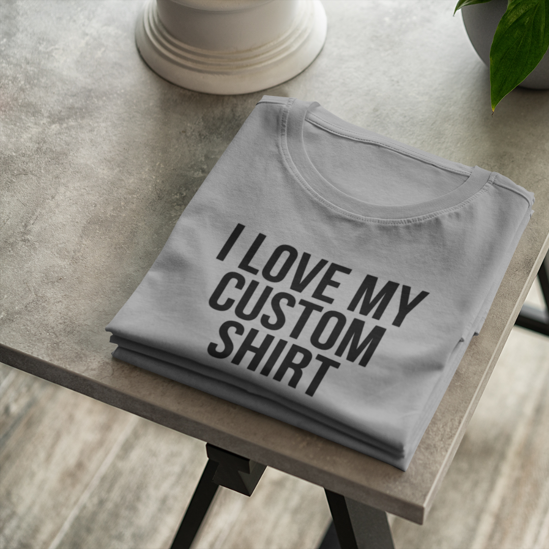 A flat-lay view of a grey custom personalized t-shirt displaying a bold black text graphic that reads I Love My Custom Shirt.