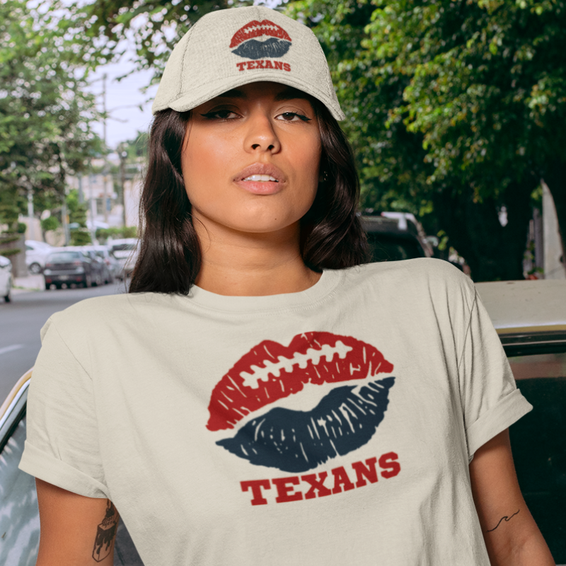 A woman wearing football t-shirt in tan color with a lip-themed design in navy bleu and maroon on top and the team name written below. 