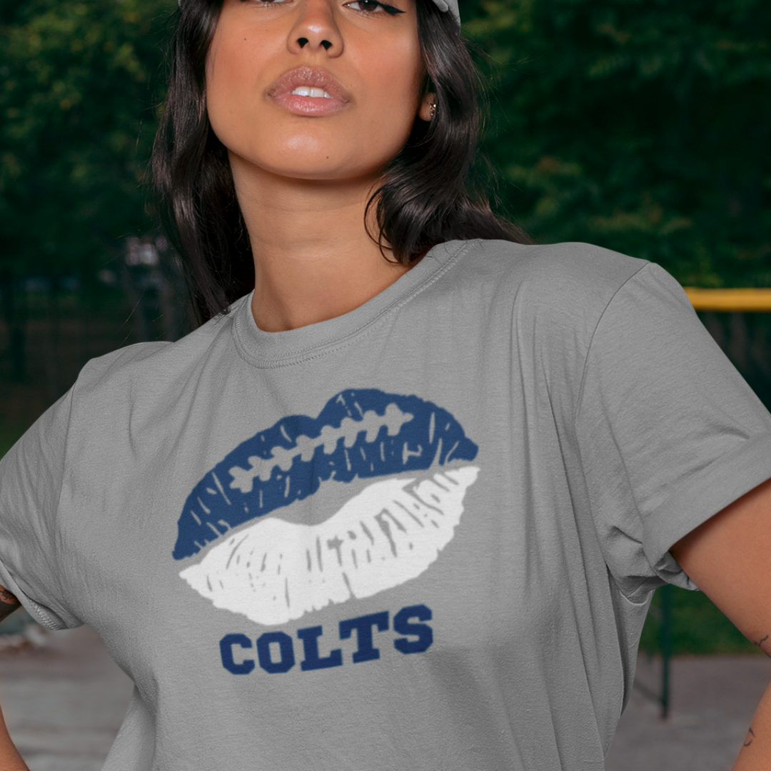 A woman wearing football game day t-shirt in grey color with a lip-themed design in blue and white on top and the team name Colts written below.