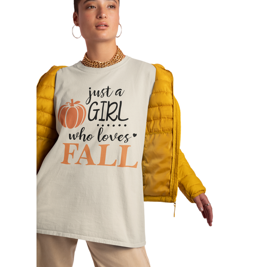 Person wearing a white shirt with Just a girl who loves fall text and a yellow puffer jacket. Available in fall colors and sizes