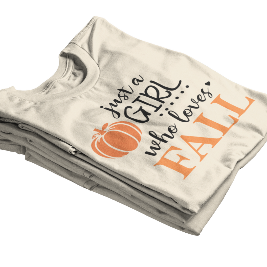 Folded t-shirt with 'ust a girl who loves Fall text and pumpkin graphic on a white background