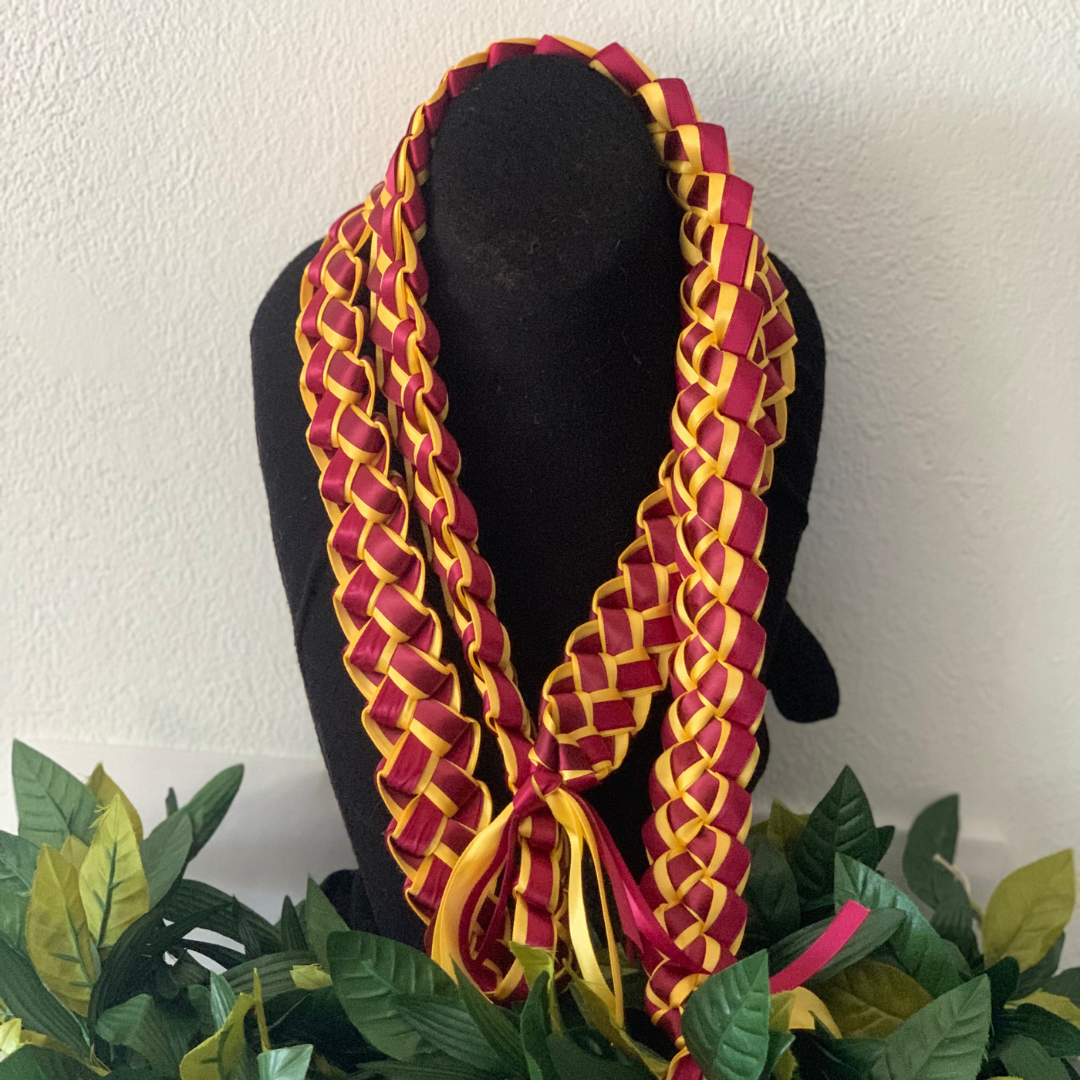 Braided graduation lei in maroon and gold school colors featuring an intricate ribbon design on a black display stand.