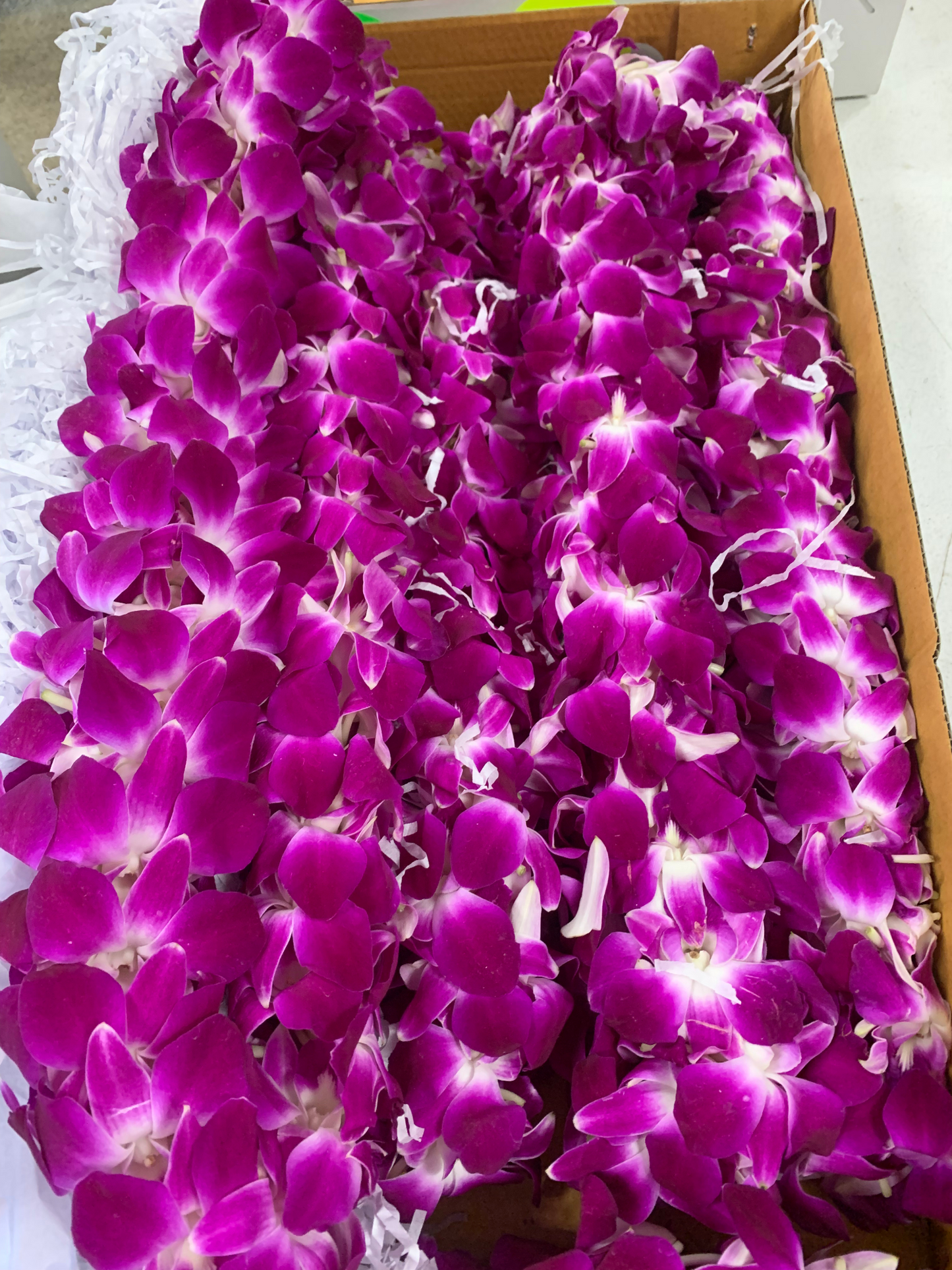 A bundle of fresh, hand-strung purple orchid leis on a clean table, crafted in Peoria Arizona from Simply Aloha On The Go
