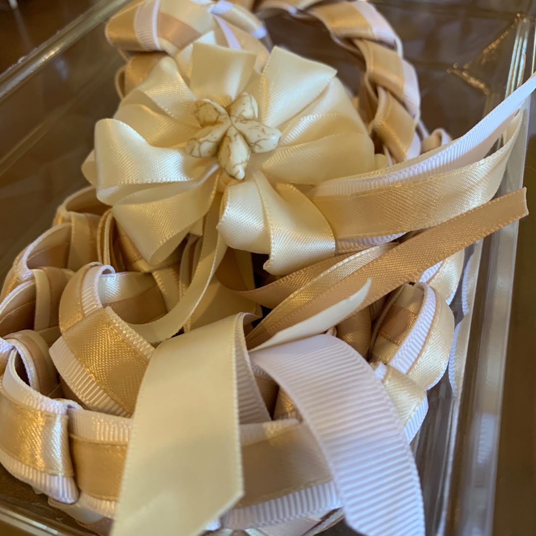 Handcrafted graduation ribbon lei in white and champagne gold featuring an elegant satin bow with a decorative flower center.