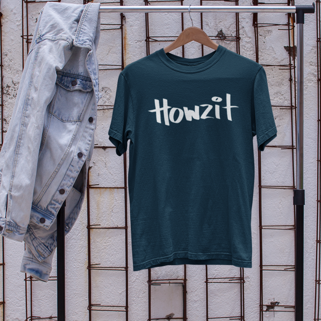 A navy blue men's t-shirt that says "Howzit" in a simple white font on a hanger, a Hawaiian slang shirt.