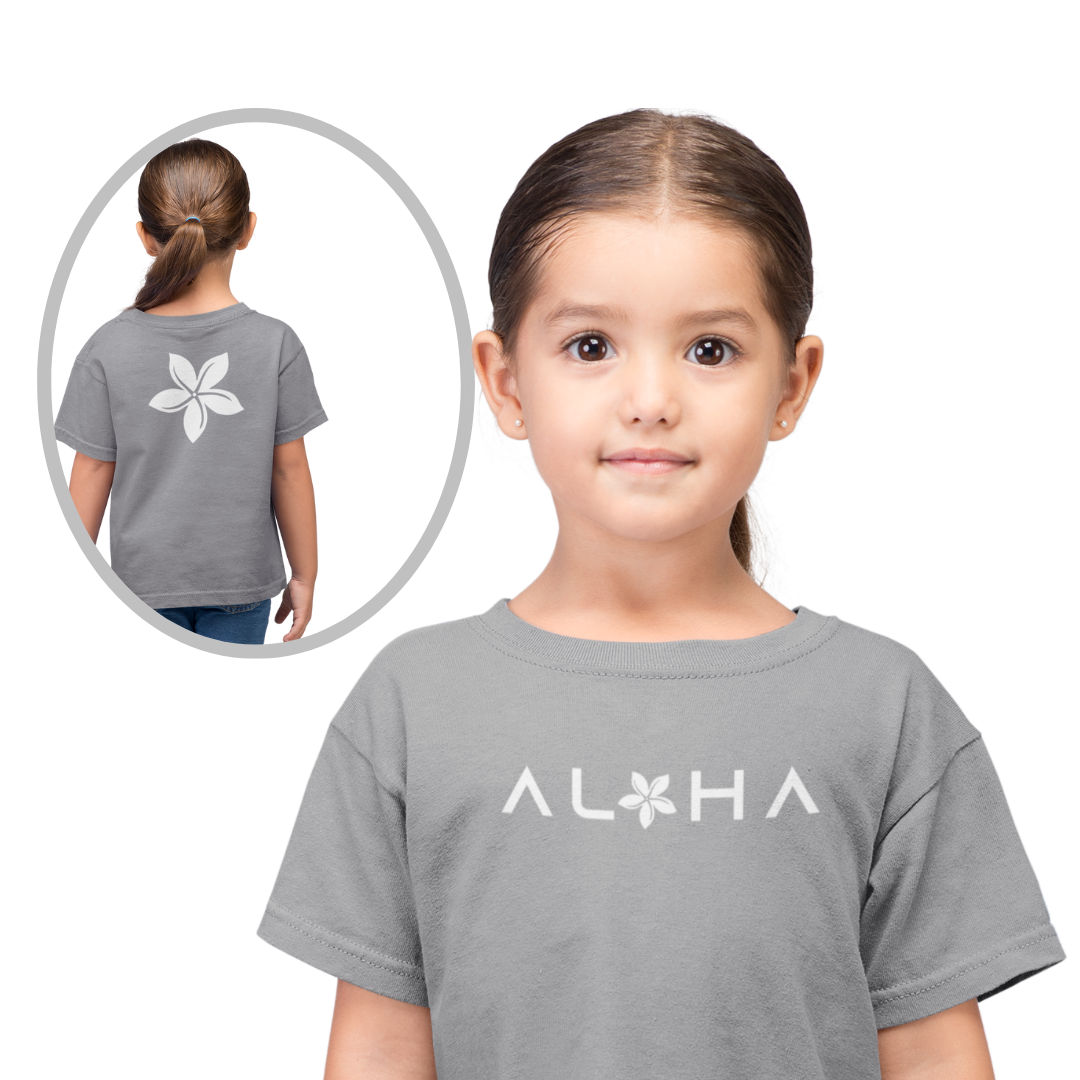 A smiling young girl wearing a grey custom kids t-shirt that displays a white chest graphic reading Aloha with a tiare flower.