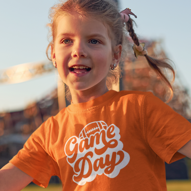 Personalized kids double-sided game day football t-shirt in orange with custom team name and number by Simply Aloha On The Go