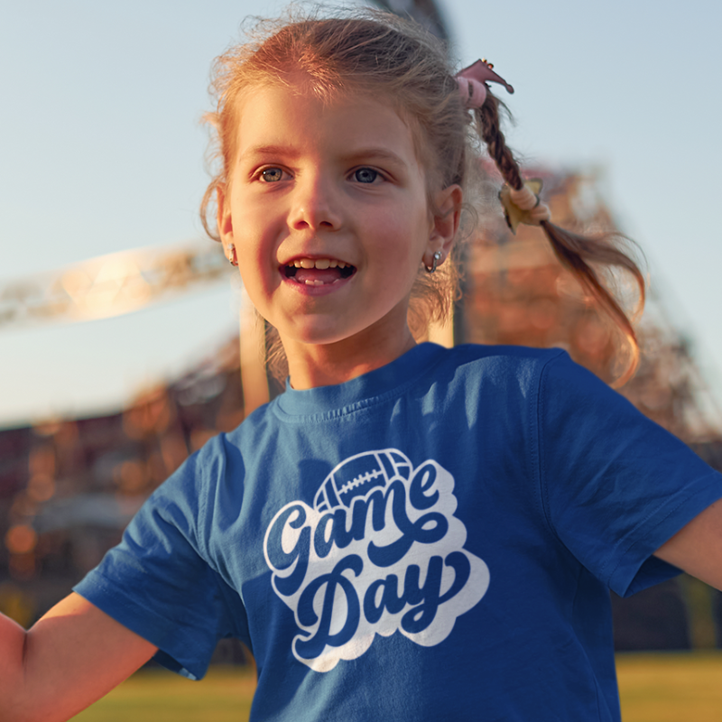 Girl wearing a blue Kids Personalized Football T-Shirt featuring a black Game Day football graphic on the front.