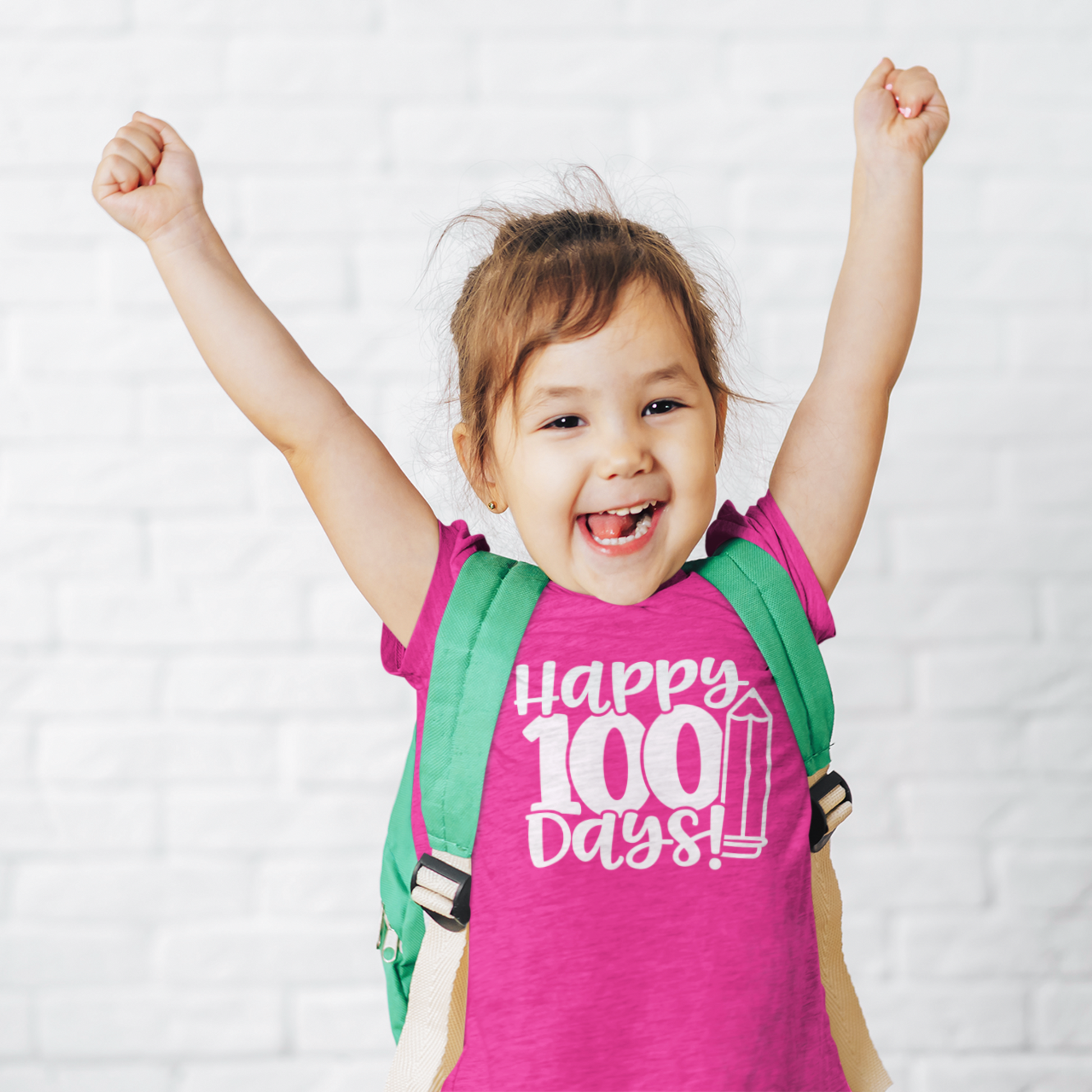 Smiling girl wearing pink Happy 100 Days kids t-shirt with backpack