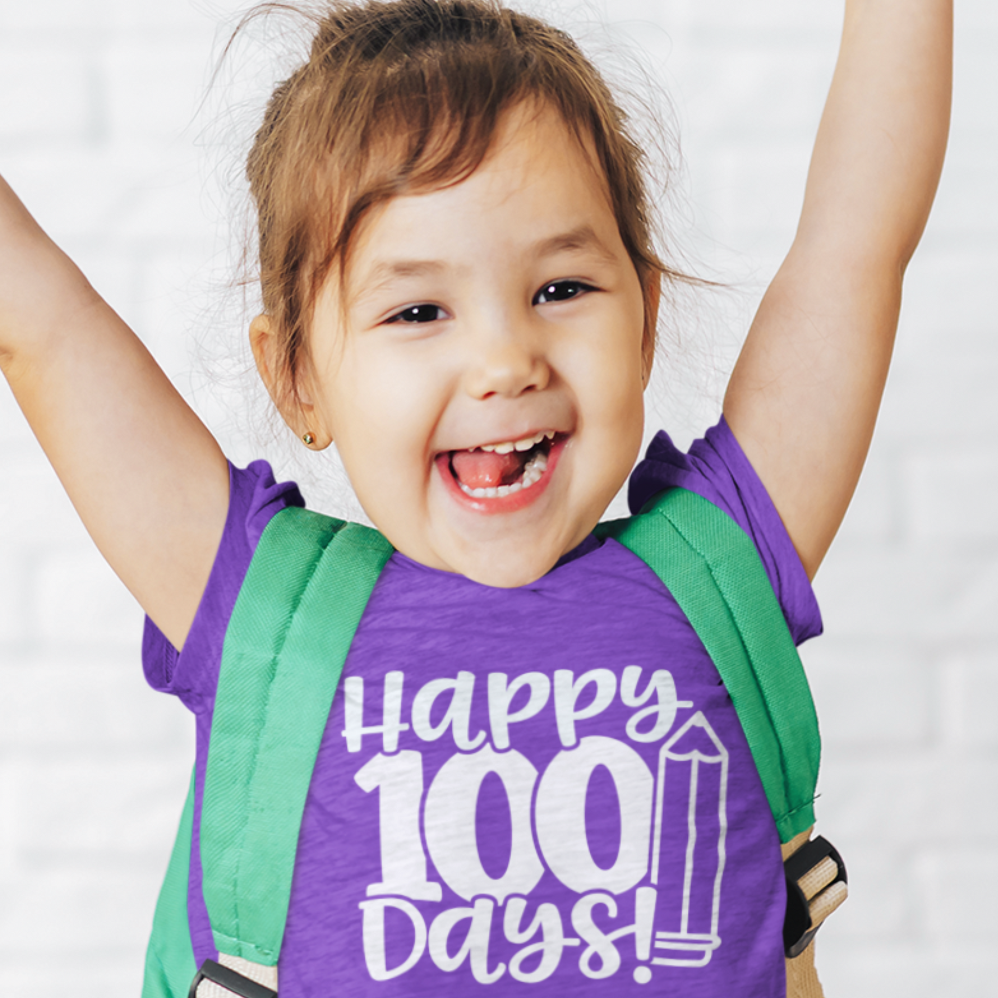 Smiling girl wearing purple Happy 100 Days kids t-shirt with backpack