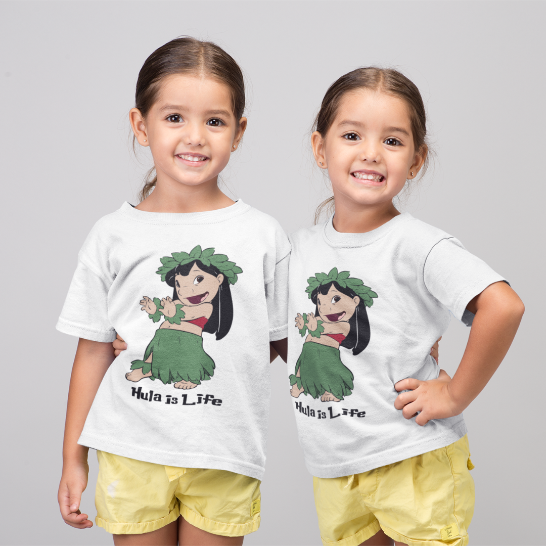 Twin young girls wearing a white t-shirt that says "Hula Girl" with a graphic of a girl dancing the hula, a Hawaiian dance shirt