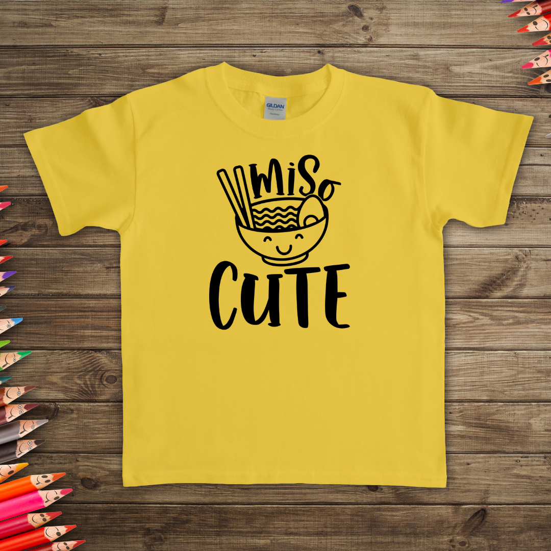 "Miso Cute" t-shirt with a graphic of a smiling bowl of miso soup on a flat lay. Available in different colors and sizes 
