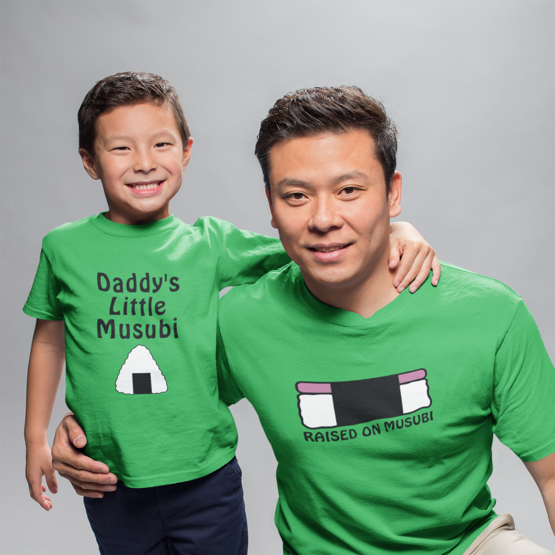 A father and son in vibrant green matching family t-shirts featuring the Daddy's Little Musubi graphic and Dad's Raised On Musubi T-shirt