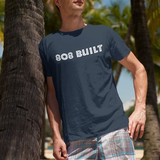 Front view of a man wearing the navy blue 808 Built Hawaii t-shirt with bold white chest text.