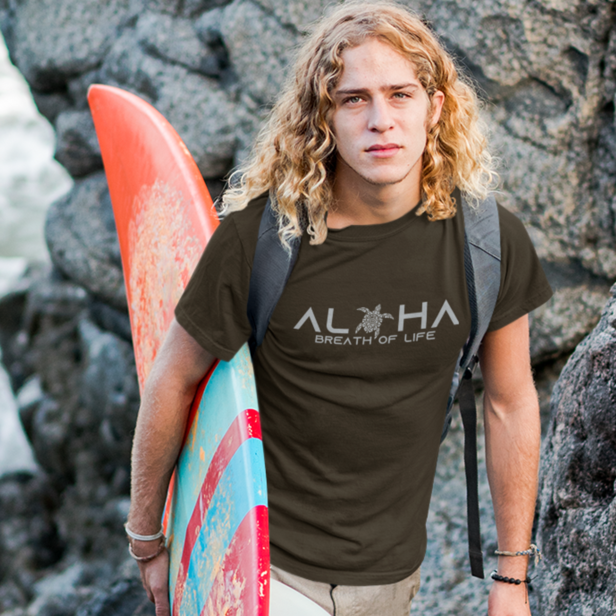 A man wearing a brown t-shirt that says "Aloha Breath of Life" in a white font, a meaningful island-inspired shirt.