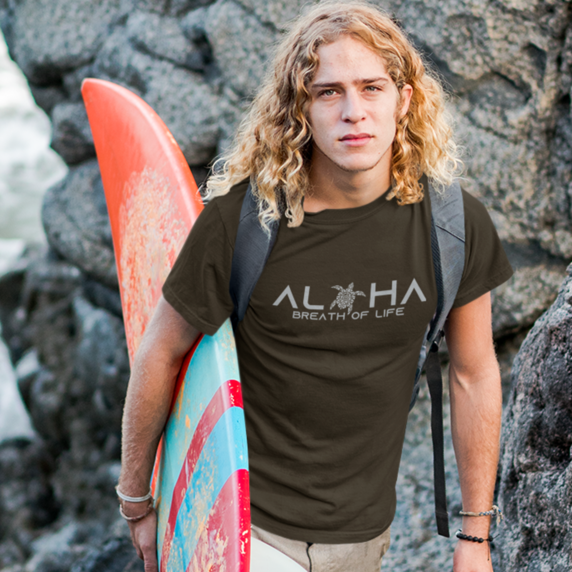 A man wearing a brown t-shirt that says "Aloha Breath of Life" in a white font, a meaningful island-inspired shirt.