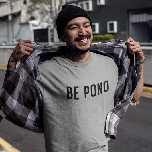 A smiling man with a grey beanie wearing a grey custom t-shirt with clean black text that reads BE PONO