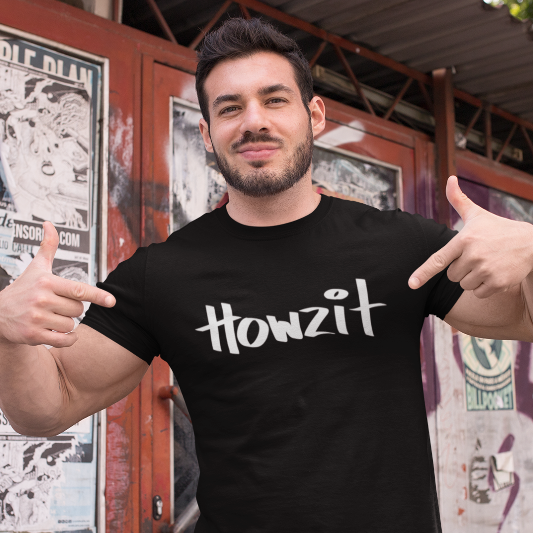 A man wearing a black men's t-shirt that says "Howzit" in a simple white font, a Hawaiian slang shirt.