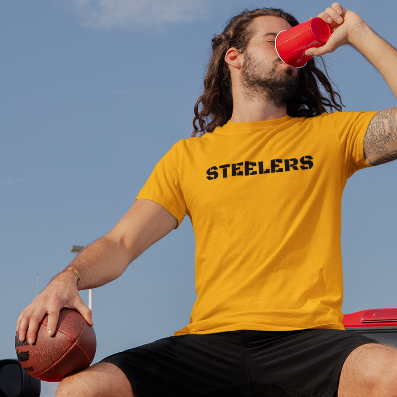 A man at a tailgate wearing a Men’s NFL Game Day T-Shirt printed horizontally with team's name – handcrafted with aloha, STEELERS fan – Simply Aloha On The Go