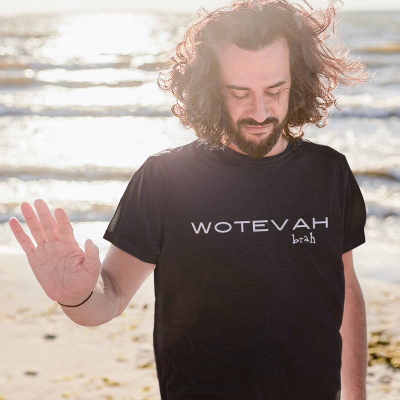 A man wearing a custom black men's t-shirt that features minimalist black block text reading "WOTEVAH brah"