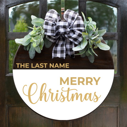 Personalized Merry Christmas round door hanger with family last name in gold lettering, buffalo plaid bow and greenery