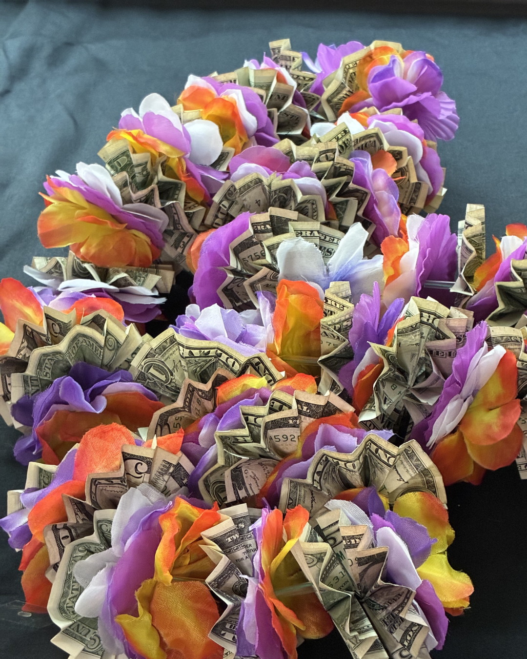 Close-up view of a custom graduation money lei showing the detailed accordion folds of the cash and the colorful layers of the silk floral petals.