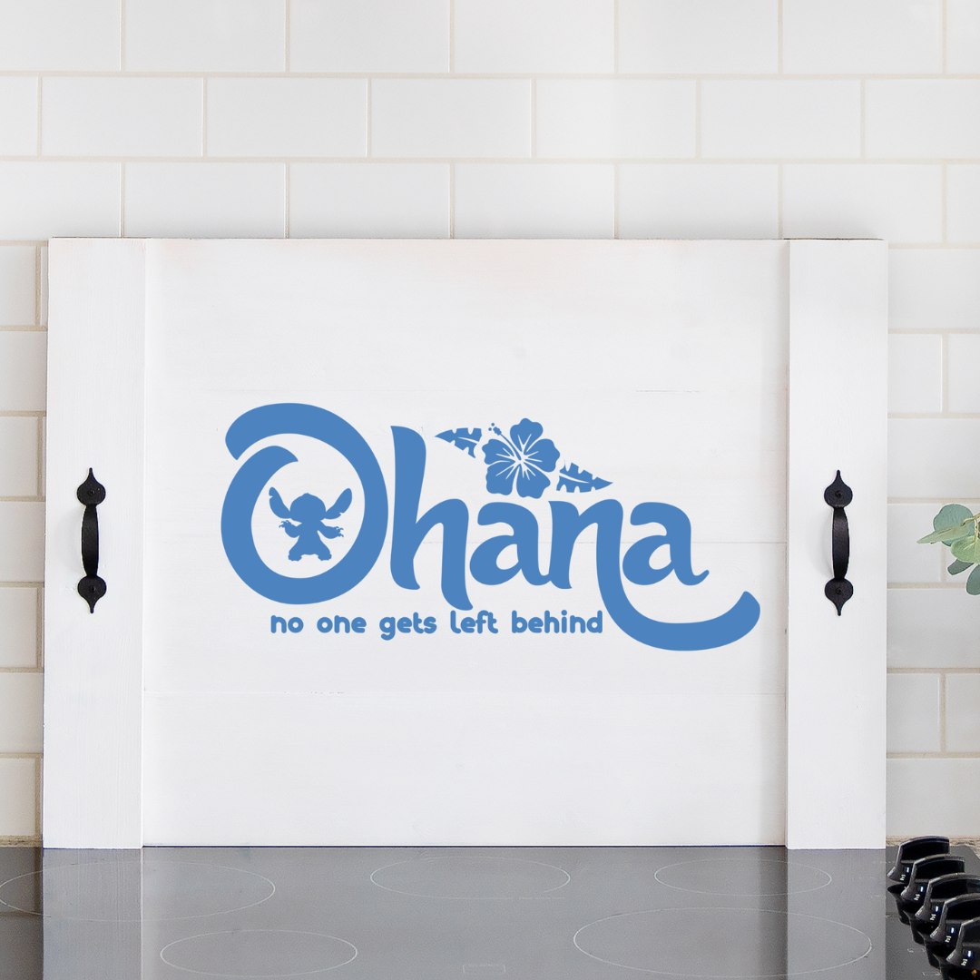 Handcrafted white wooden noodle board featuring blue "Ohana" font stenciled design on a stove top, used as a kitchen counter space saver and serving tray.