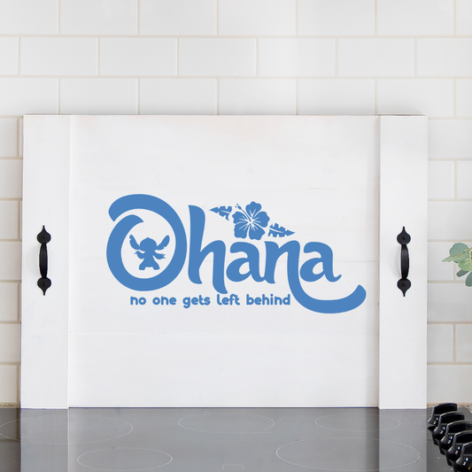 Handcrafted white wooden noodle board featuring blue "Ohana" font stenciled design on a stove top, used as a kitchen counter space saver and serving tray.