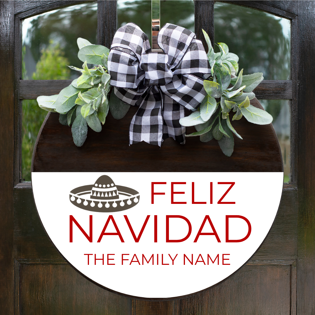 Personalized Feliz Navidad Christmas round door sign with bright greenery and custom family name in red font on a stained and white background