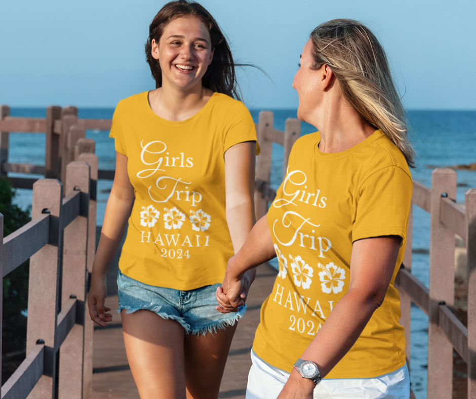 Two women wearing matching personalized "Girls Trip" t-shirts on vacation